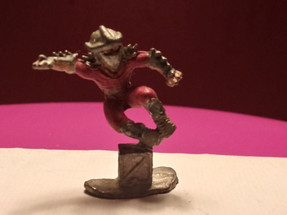 A lead miniature of Shredder from TMNT (Mirage Vol 1 design) jumping over a crate.
