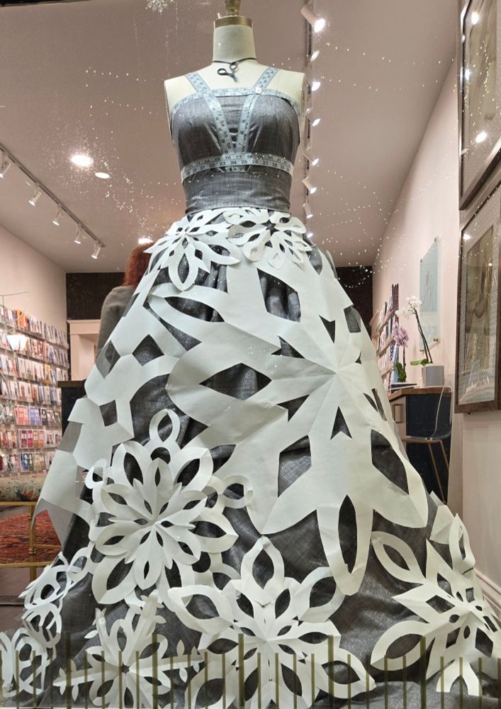 Picture of a dress made from large cut-paper snowflakes, in the store window at Stitch Sew Shop in Old Town Alexandria