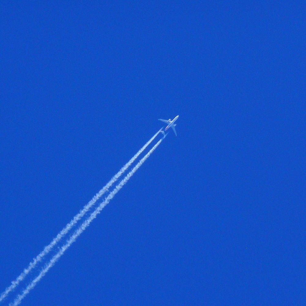 a plane leaving a vapour trail across a clear blue sky