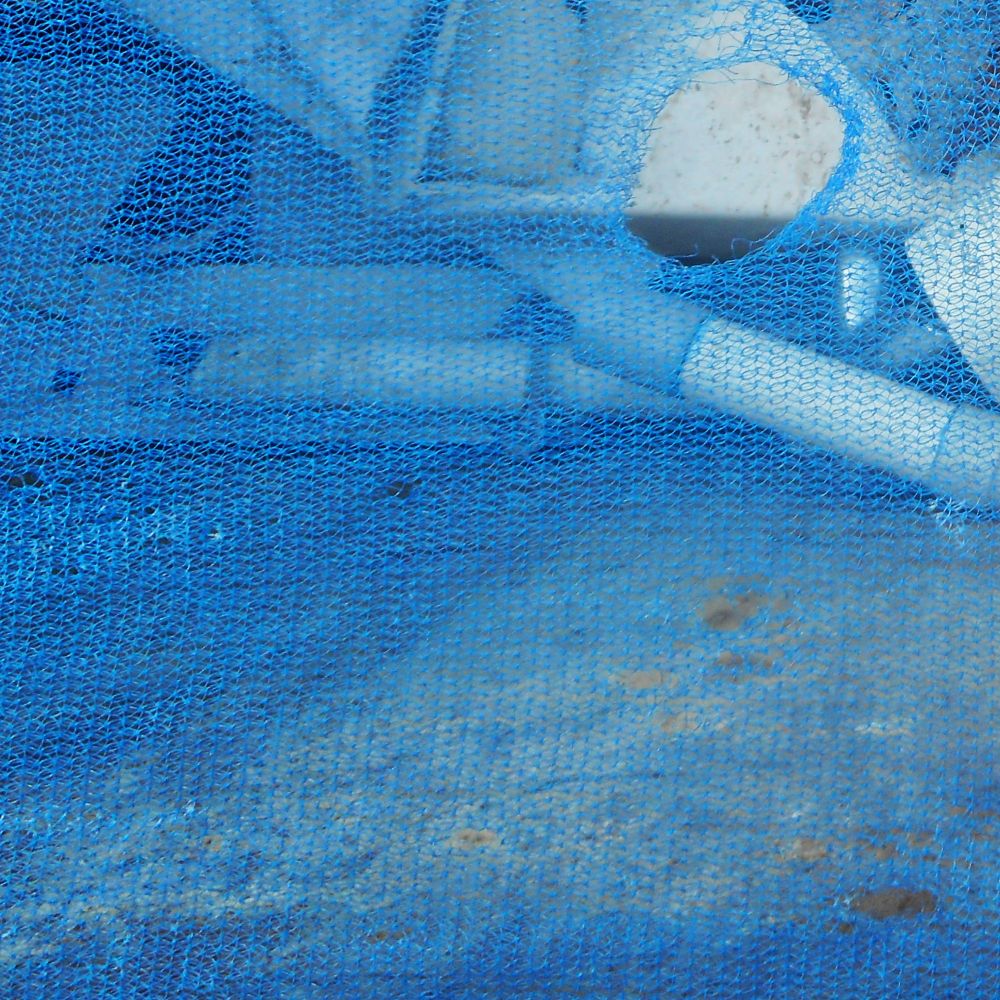 torn blue netting in front of a pile of rubble
