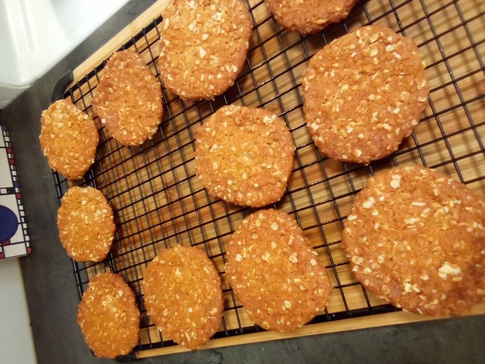 Golden Anzac biscuits cooling on a rack.