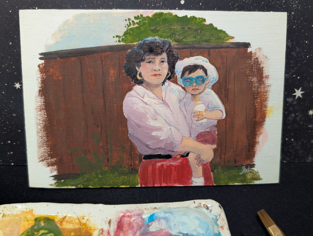 Gouache painting on wood panel of a young Asian woman holding her toddler. The woman has short wavy permed hair, hoop earrings and  pink lipstick. She is wearing a loose blouse and red skirt with a black belt. Her child is wearing a white bonnet, white polo shirt, pink shorts and bright blue, oversized sunglasses. She is holding a small baby bottle. They are standing in front of a fence with small plants in front and a tree and blue sky visible behind.