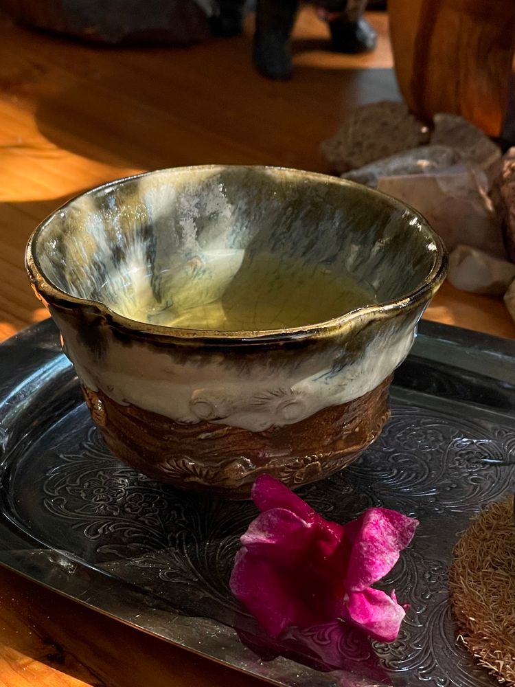 Ceramic cup of oolong tea, dramatic light and shadow, next to a dark pink snapdragon flower