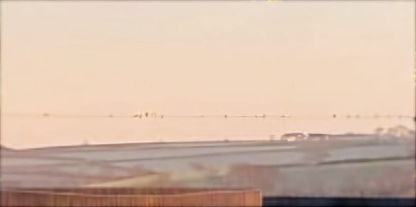 Frosty view across the hills with birds on the wire. Orange sky. 