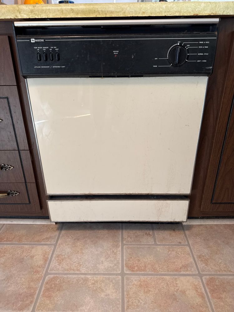 An old cream colored dishwasher that has seen it all