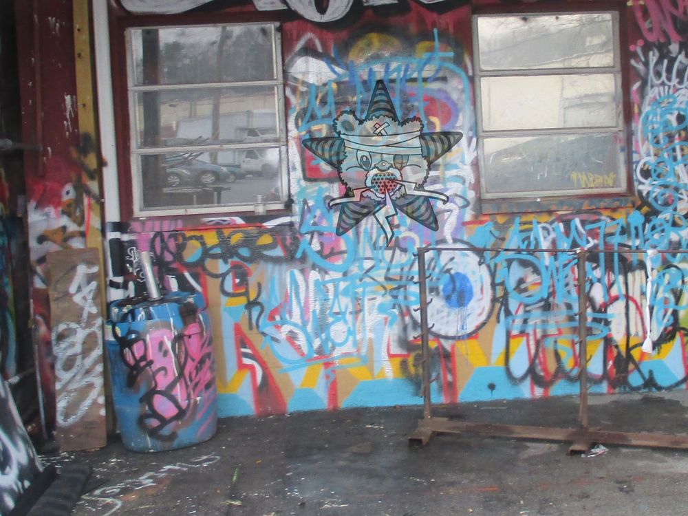 A graffiti-covered corner of some shack, with the Self Help Radio logo on the wall too.