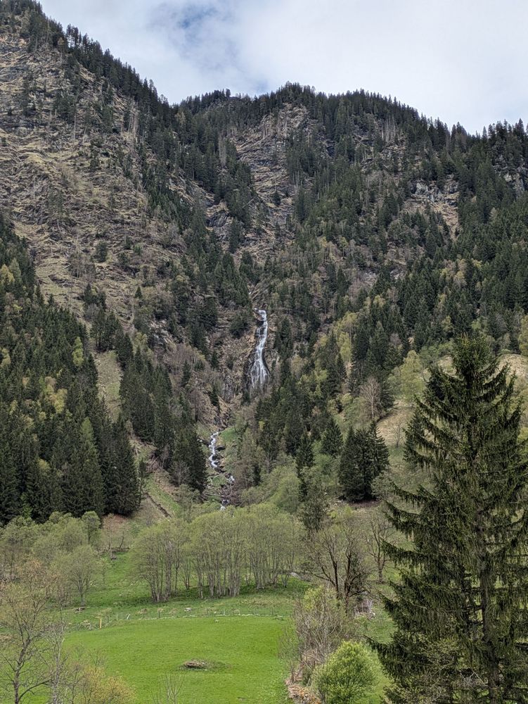Spärlich bewaldete Berge, von einem kommt ein Wasserfall herunter