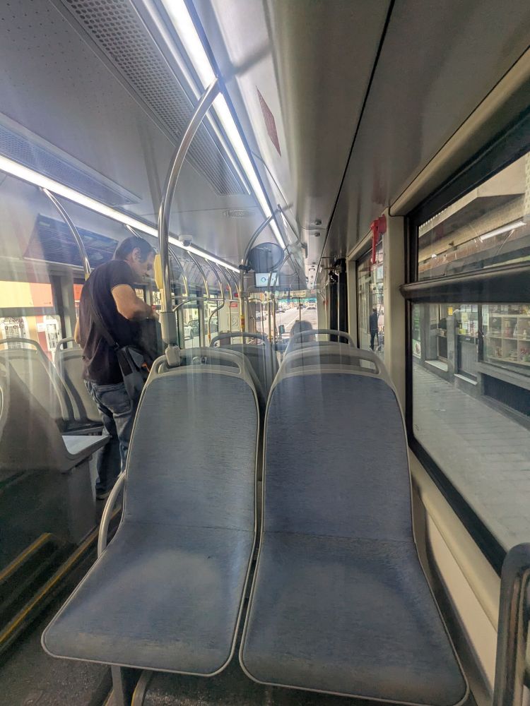 Interior of a bus, from the rear of the cabin looking forward.