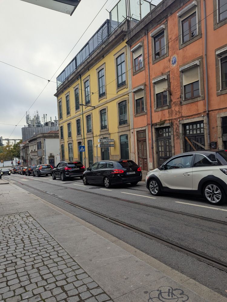 A photo showing a queue of traffic down a street with well established and operational tram lines.