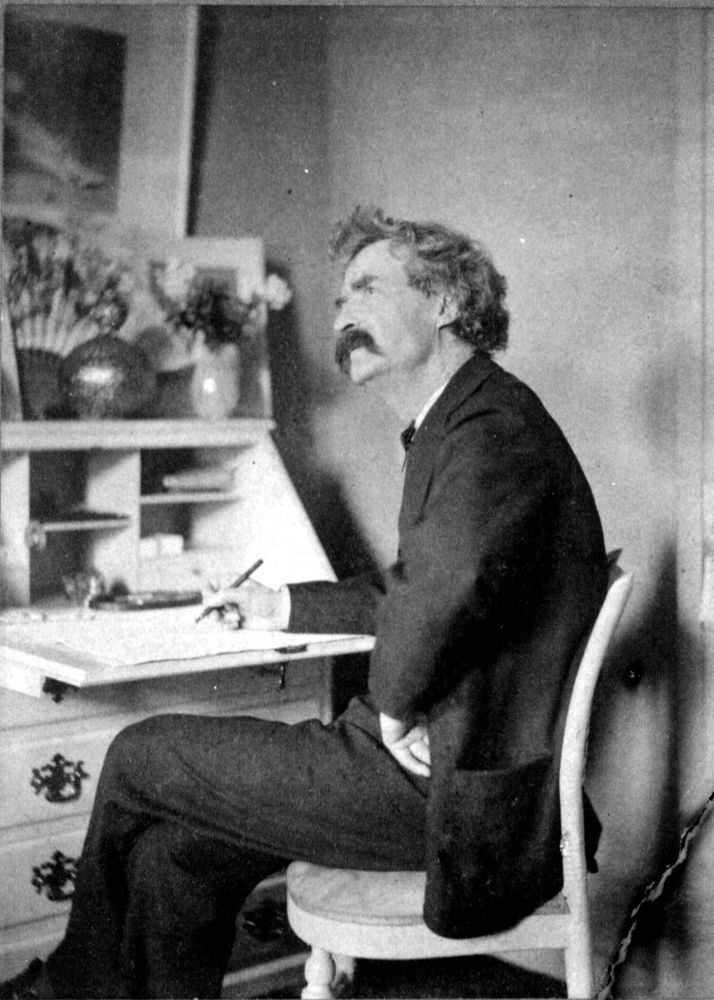 Samuel Clemens aka Mark Twain, pondering and writing in his study. Black and white photograph. Mark Twain in full suit.