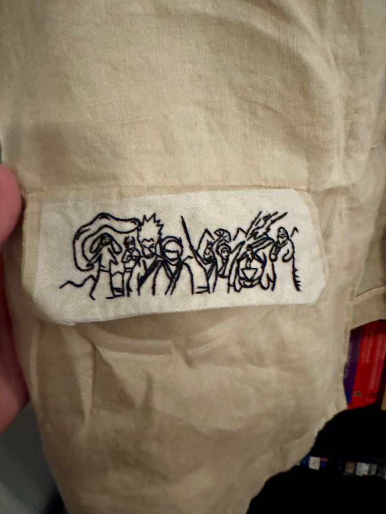 Black embroidery on pocket flap of linen blazer. 

Reference: Avatar The Last Air Bender. 