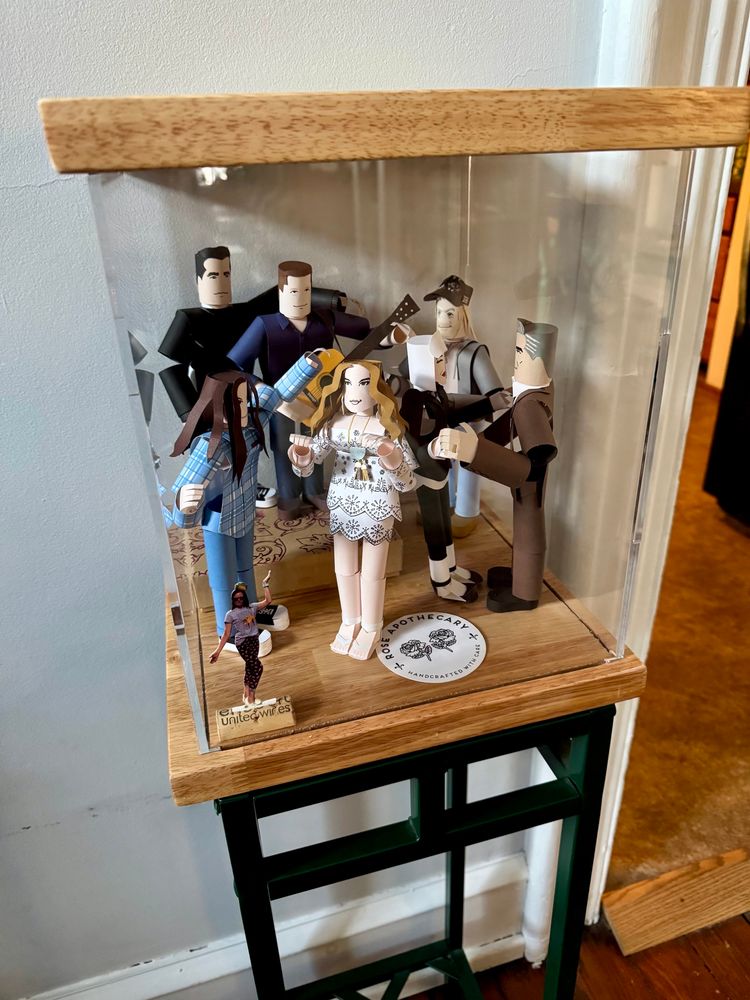 Slightly different angle of a display case containing paper figures of characters from Schitt’s Creek, posed in dancing positions. 