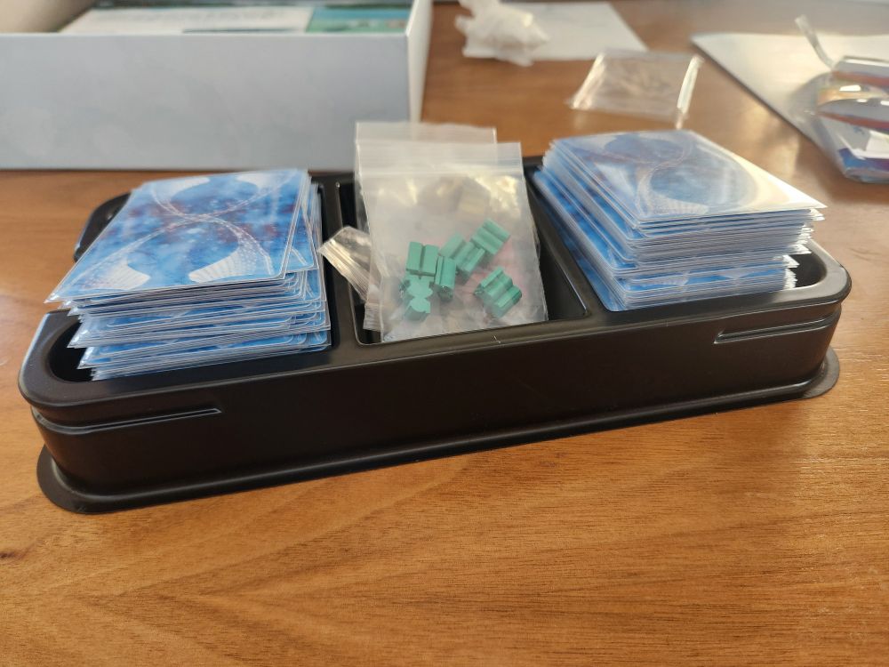 The card tray for Finspan. The deck has been sleeved, split in two, and placed in the wells designed to hold them.... and they don't fit. The two stacks of sleeved cards rise significantly higher than the card tray, so much that thry can't even be compressed enough to fit.