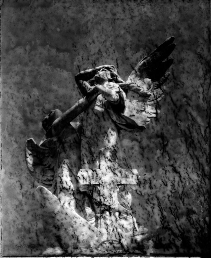 a decayed polaroid negative of a cemetery statue with two angels