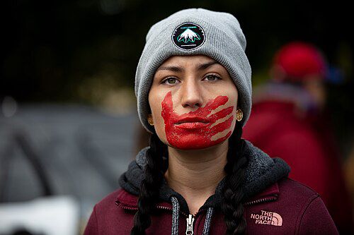 Native Woman with red hand print across mouth