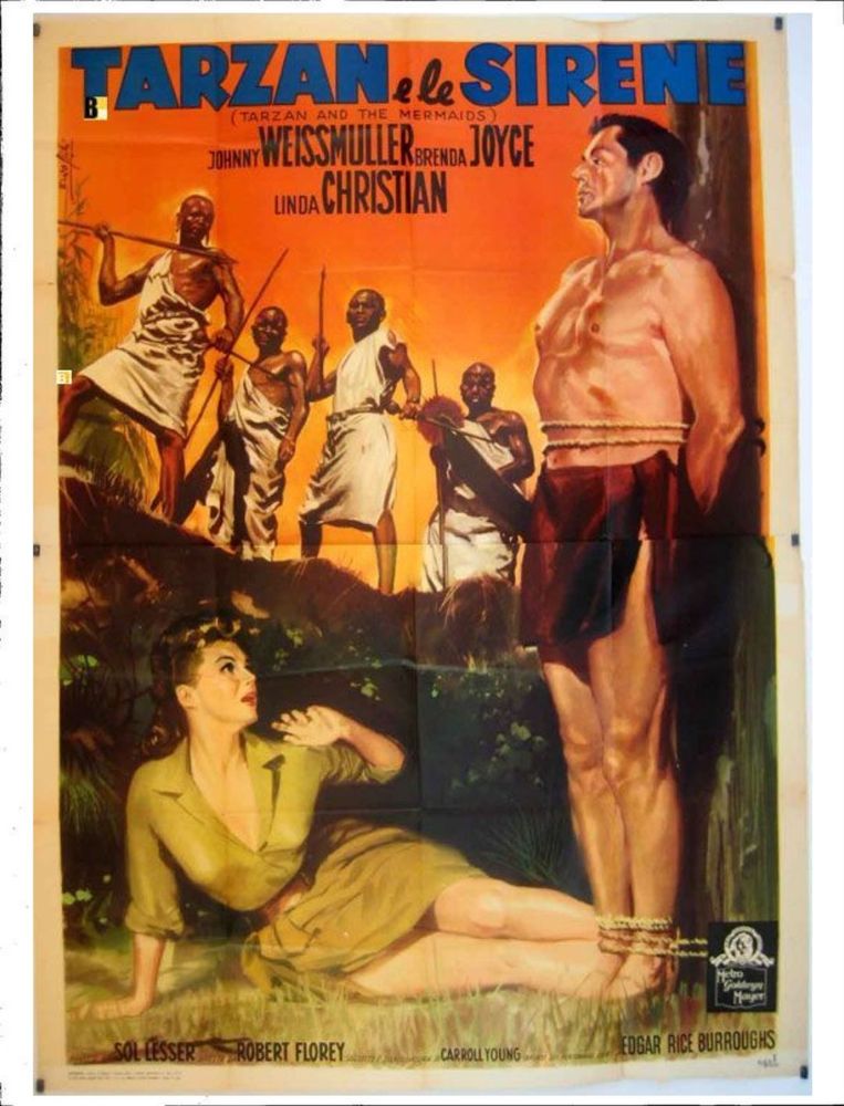 Tarzan bound to a stake. A woman sprawls at his feet. Several native warriors stand menacingly on a ridge.