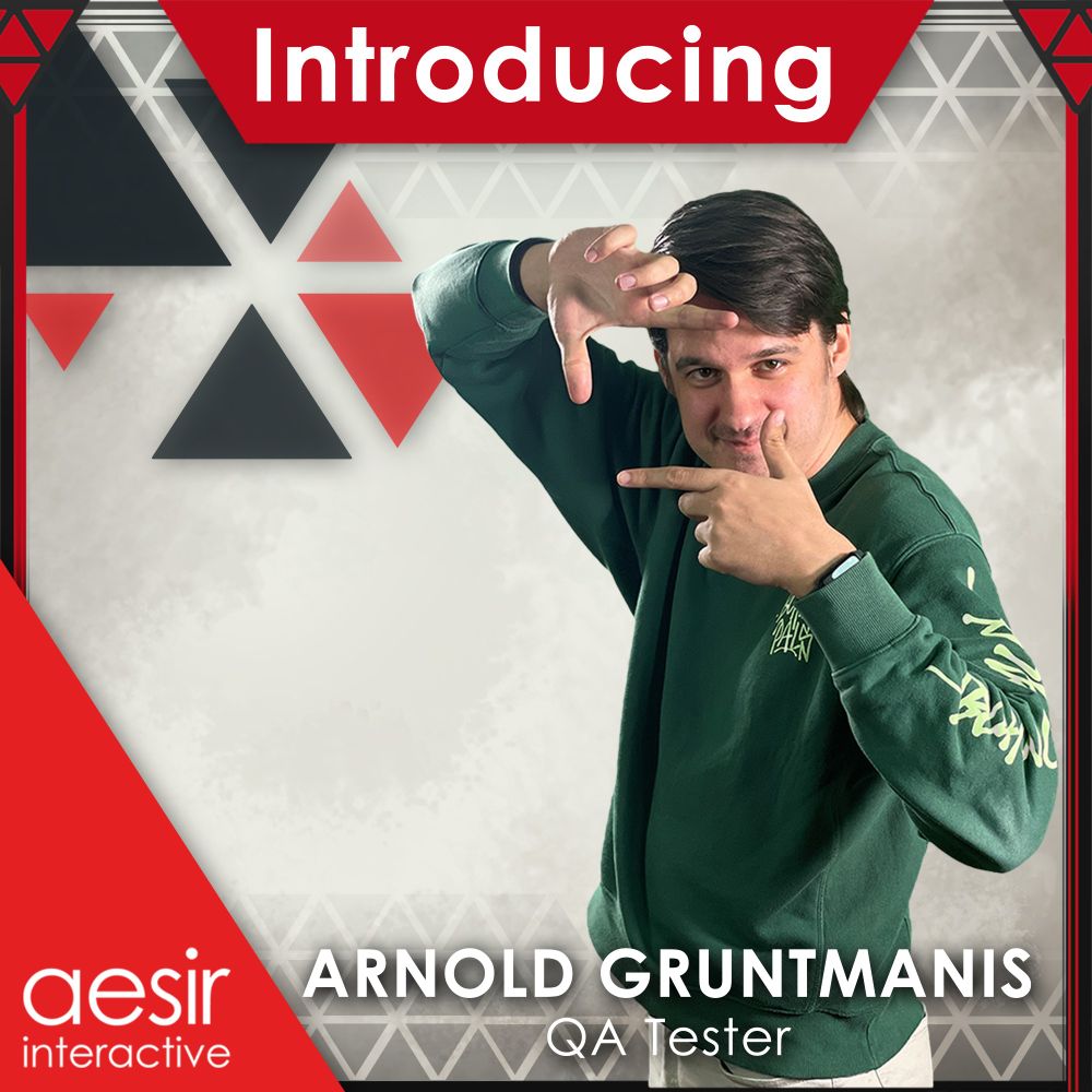 Image of an employee smiling into the camera, standing 45 degrees. He poses with his two hands a frame in front of his face for the camera. They are surrounded by a graphic banner which says "Introducing", "Arnold Gruntmanis", "QA Tester", and "Aesir Interactive".