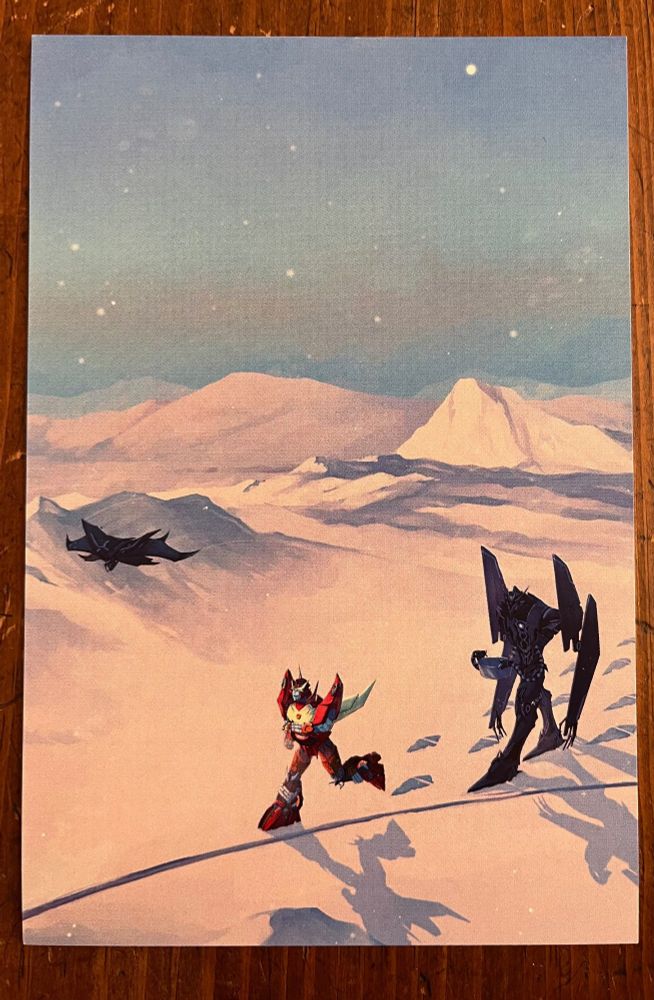 Photo of a print of Rodimus and Soundwave on Enceladia. The background is of snow, with some snowy peaks, and a painted light blue sky with stars. Rodimus runs ahead of Soundwave joyfully. Laserbeak flies just ahead of him. Soundwave follows behind, holding a metal container with his tentacles. Their shadows fall over the snow and they leave footprints behind them.