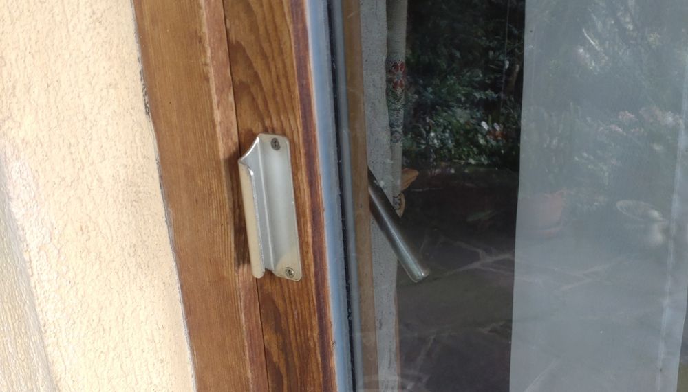 Silberner Türgriff an einer Holz-Glastür