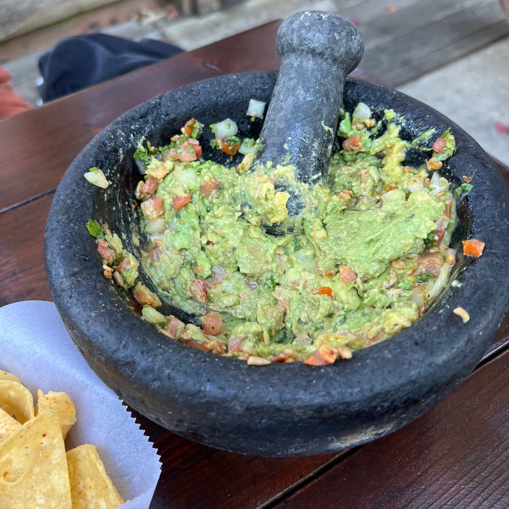 Tableside molcajete de guacamole with chips on the side. 