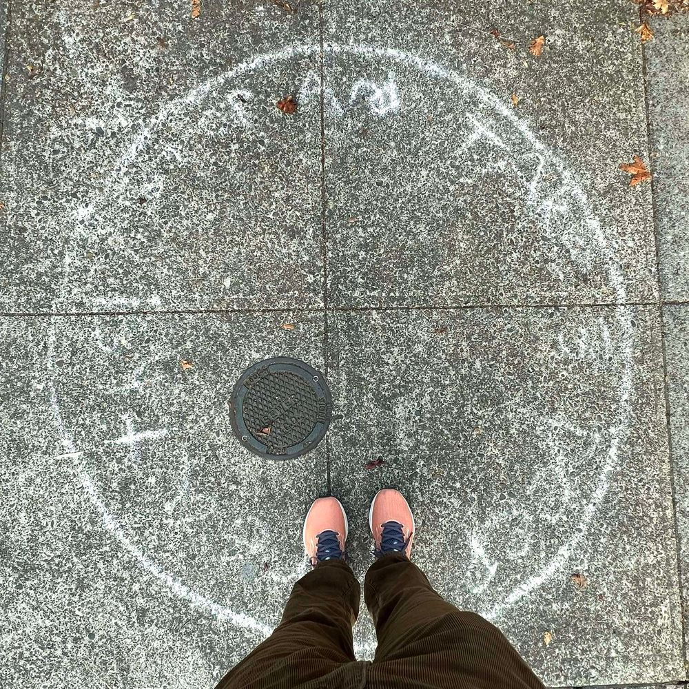 Top down view of two legs with orange shoes in a chalk circle with the words "Step and take a deep breath" written around the inside of the circle.  