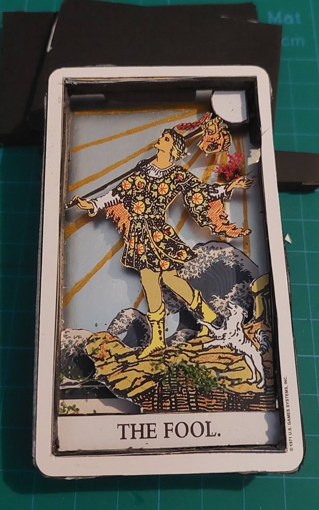 photo of the Fool card - the card has been cut so that it is now 3d, the back is silver with a collage of a wave from some origami paper... there are also some additional moss and flower bits added in