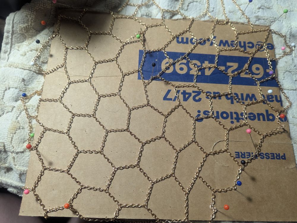 Hexagonal necklace chain pinned to a piece of cardboard. My current project for school!