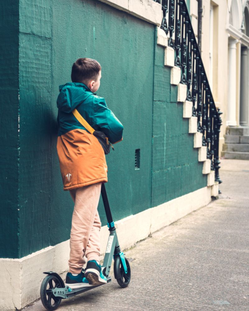 Young lad waiting on scooter for mum to come out of shop. 