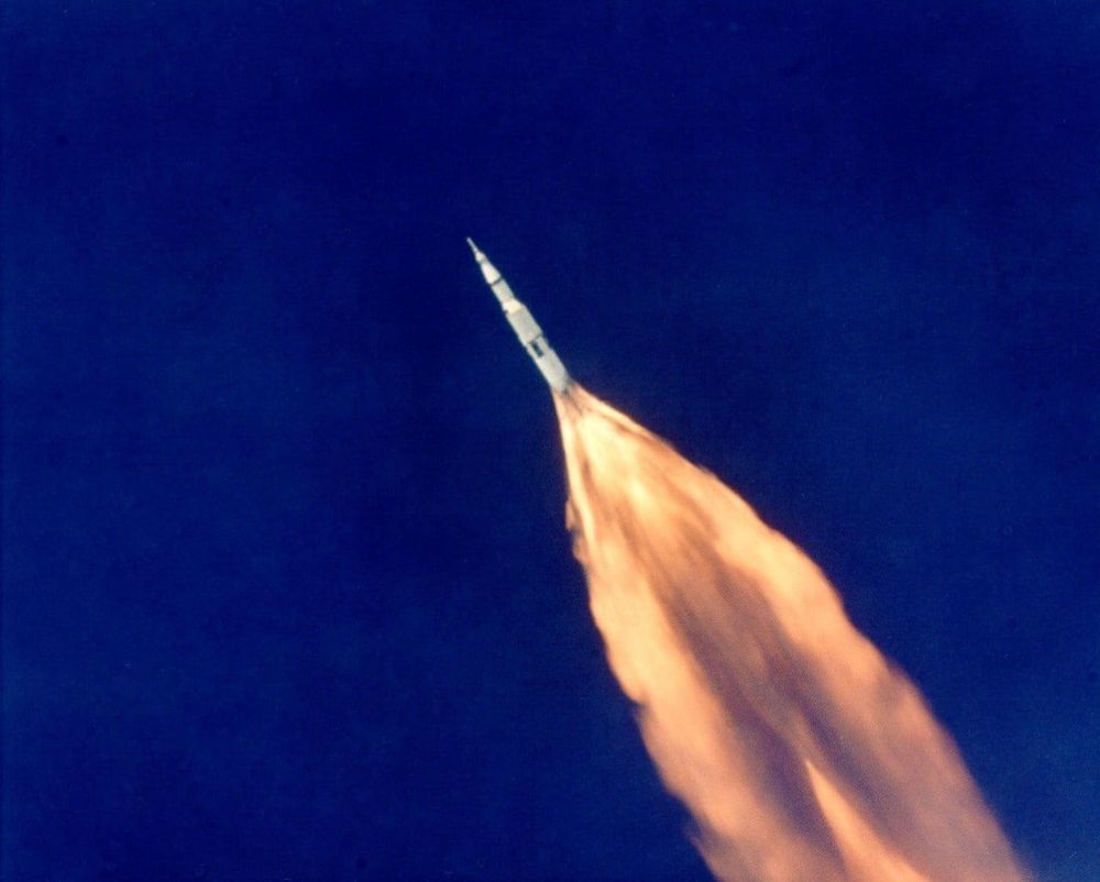 Picture taken on July 16th 1969.   It is a heavily zoomed in shot of the deep blue of the sky at high altitude combined with a tint to protect against the brightness of the rocket blast.  In the centre of the picture is the Apollo 11 Saturn V rocket before any stage separation (which occurs at about 61km altitude)...   The flame of the main rocket boosters leaves a trail of flame that reaches to the corner of the picture.