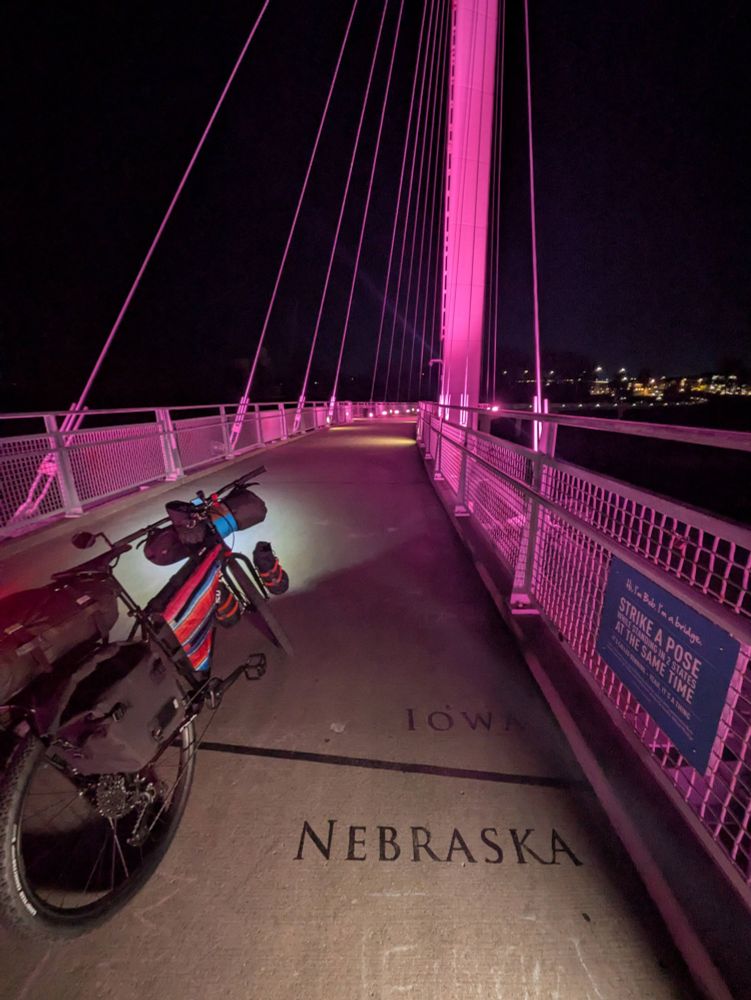 Bike on pedestrian bridge lit pink before dawn, a bike straddles the line between Nebraska and Iowa