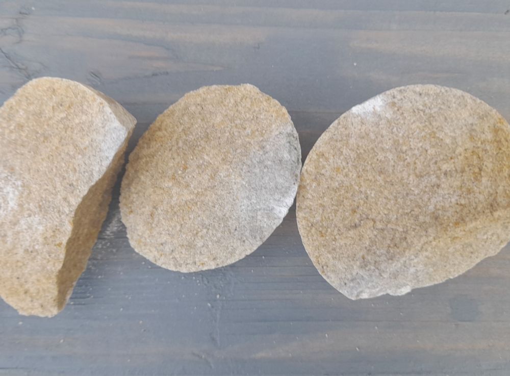 Round stone broken in 3 to reveal sandy coloured interior.