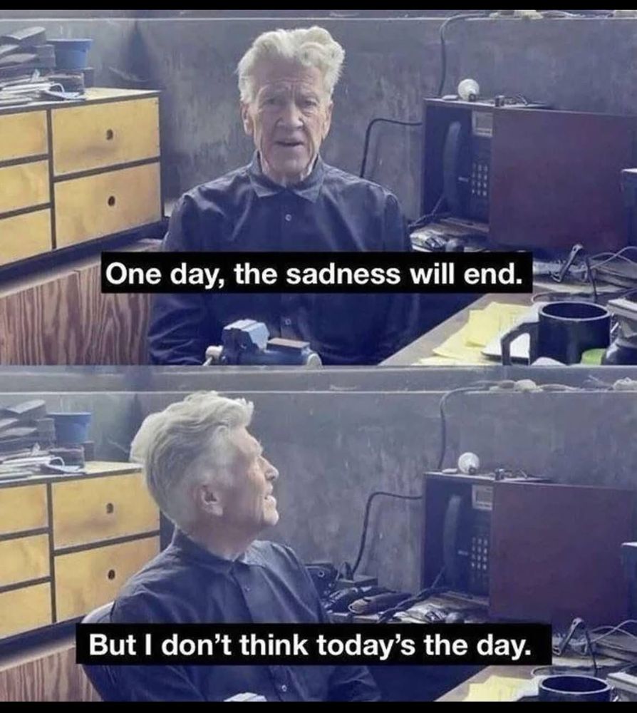 Two shots of David Lynch, one of top of the other. He is sitting at a desk with grey walls and a yellow cabinet behind him. The first shot is captioned "one day, the sadness will end." And the second is captioned "But I don't think today's the day."