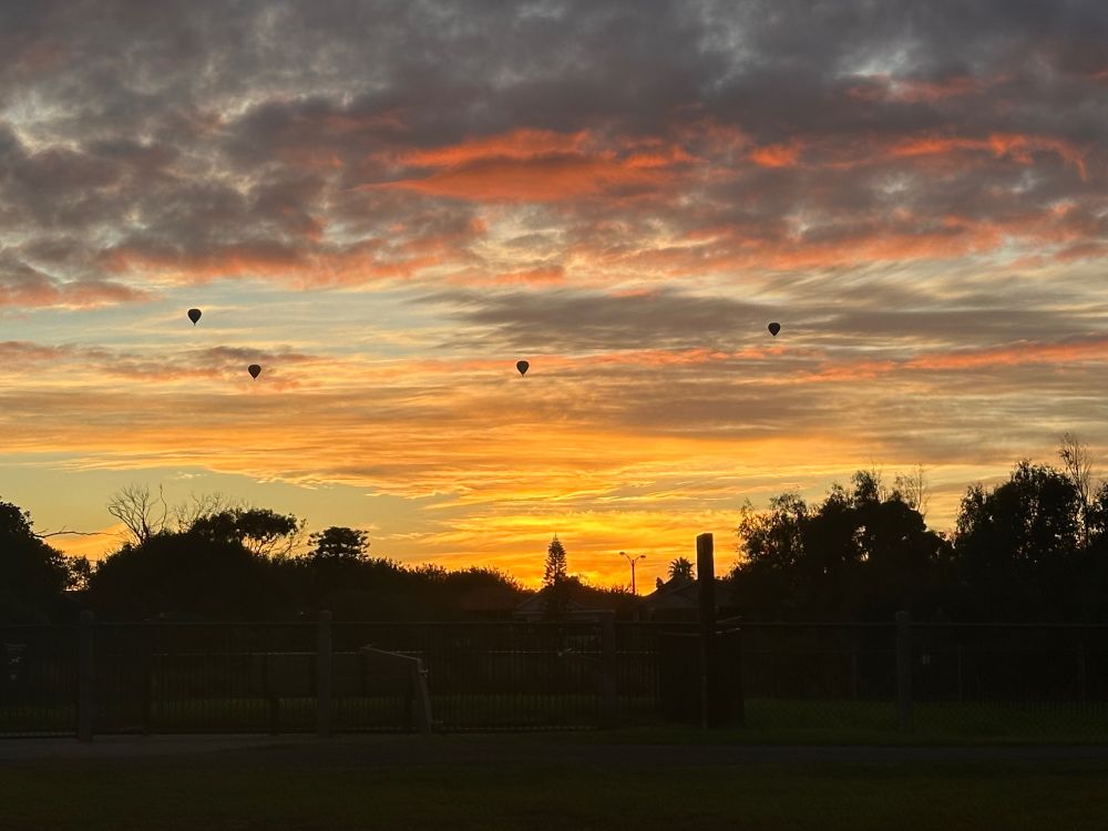 Pink and orange clouds at sunrise. Hot air balloons enjoying the calm Autumn morning. 