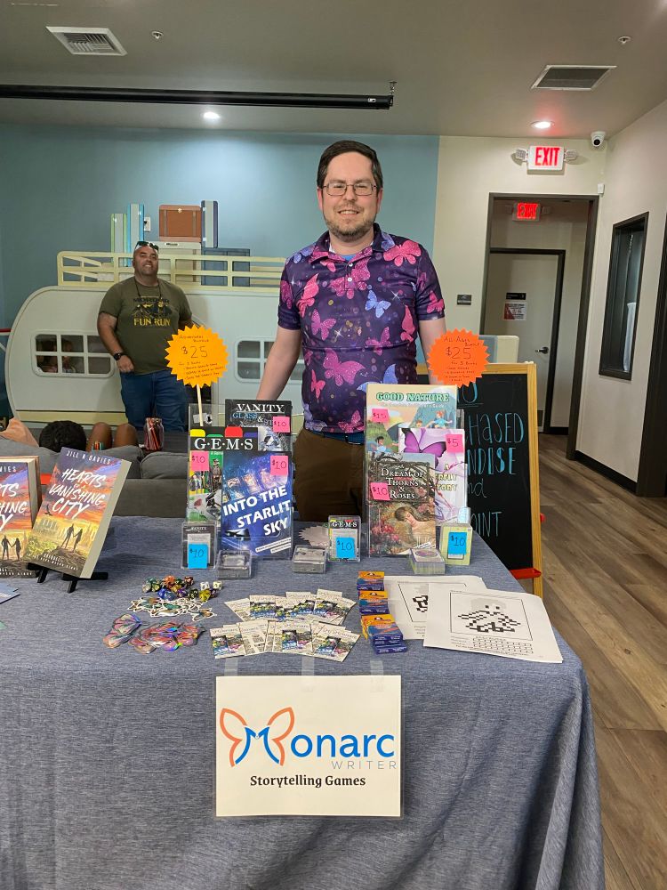 The author stands at the MonarcWriter table at the authors fair.