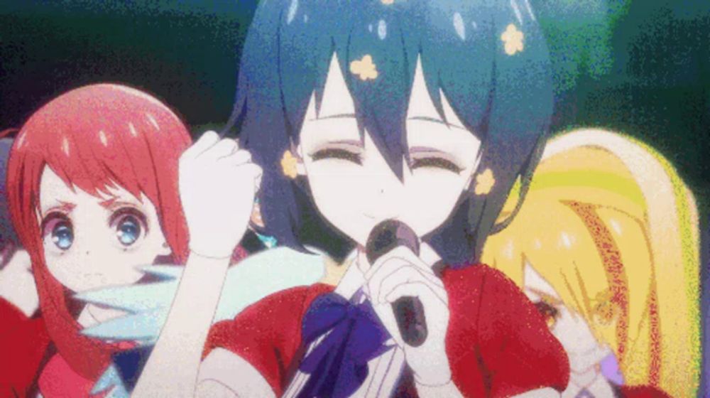 a girl with blue hair is singing into a microphone in front of two other girls