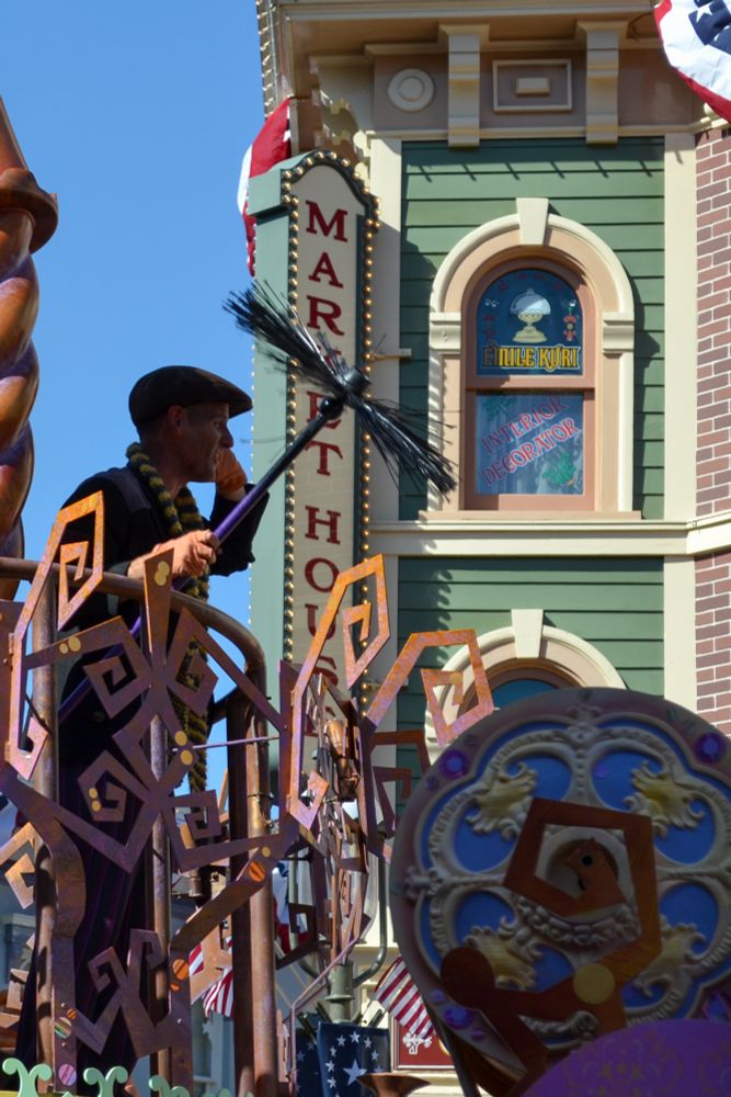 Photograph of Kevin Kidney as a chimney sweep in Mickey's Soundsational Parade at Disneyland, with the Market House on Main Street, U.S.A. as a backdrop.