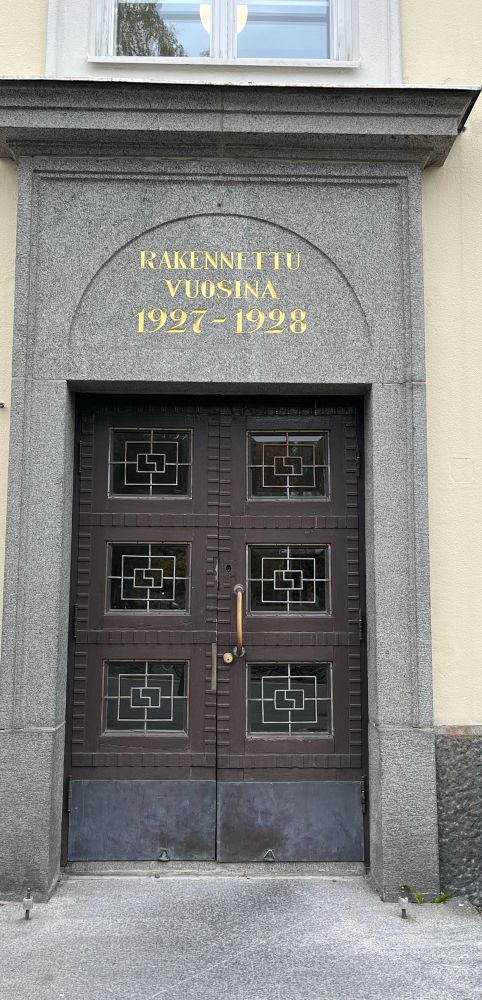Jyväskylän Normaalikoulun ulko-ovi, jonka yläpuolella kullattu teksti ”rakennettu vuosina 1927-1928