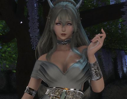 Rhenia, padjal, stands outside in front of a wisteria tree. She has gold bangles and a gold choker and a large gold midsection accessory-like belt with a green gem in the middle. She stares at the pov. Her neckline is also plunging.