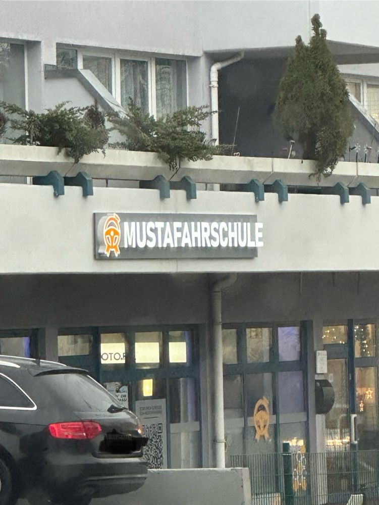 Zu sehen ist ein Werbeschild einer Fahrschule mit dem Namen „Mustafahrschule“.