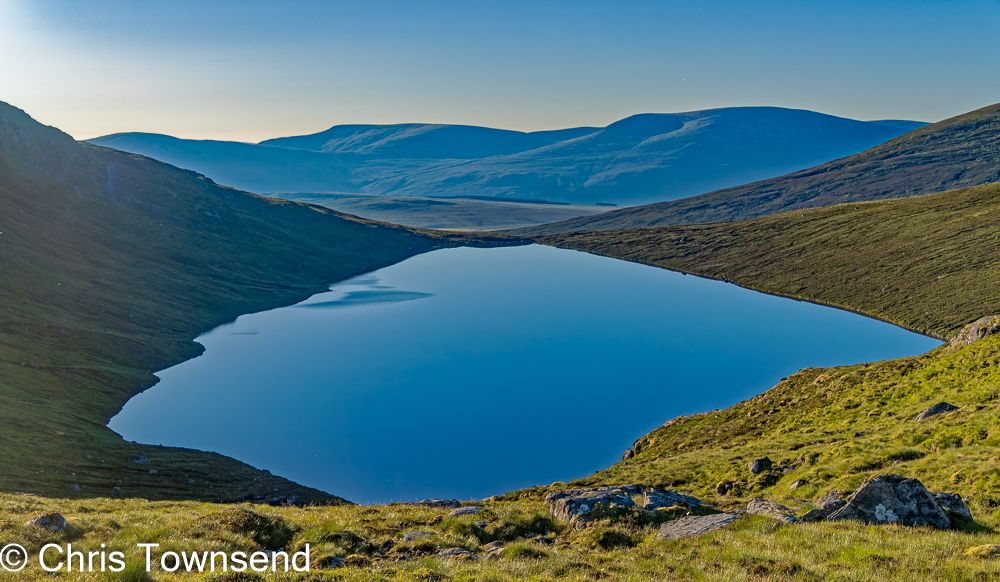 A loch in the hills at dawn under a clear sky.