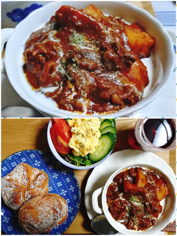 2025/10/31　の晩ごはんの写真。
白いグラタン皿に盛られたビーフシチューがメイン。表面に生クリームを垂らしてある。
一人分のトレイには、スーパーで買ったタカキベーカリーの米粉石窯パンが2個。丸くて表面に白い粉が振られている。
赤ワインの入った背の低いグラス、トマトときゅうり、ベビーリーフのうえに乗ったミモザサラダ。ドライパセリを振ってある。