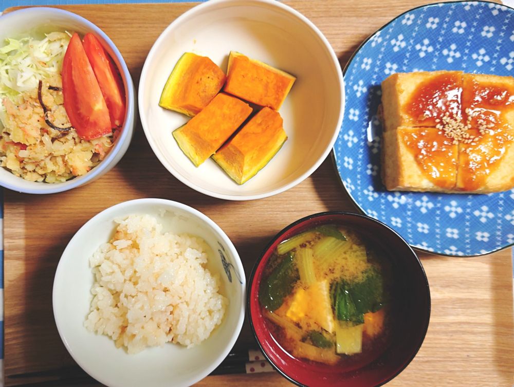 一人分の夕食が乗ったトレイの写真。カットキャベツにくし切りトマト1切れ、和風ポテトサラダを添えた小鉢。北海道の雪化粧かぼちゃをレンジで蒸したもの。「焼いて美味しい絹揚げ」1枚を焼いて生姜じょうゆの餡をかけたもの。小松菜と豆腐の味噌汁、昨日のシンガポールチキンライスの残りごはん。