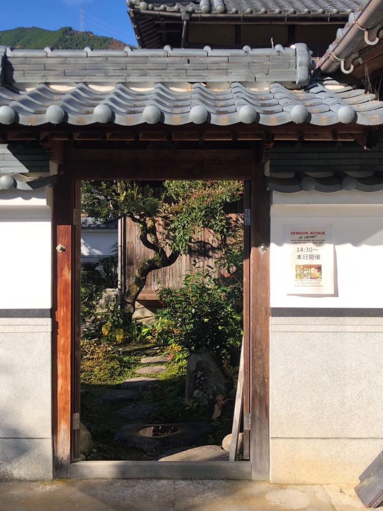 An open doorway to a Japanese style garden. An event poster for a Denison Avenue reading at 2:30