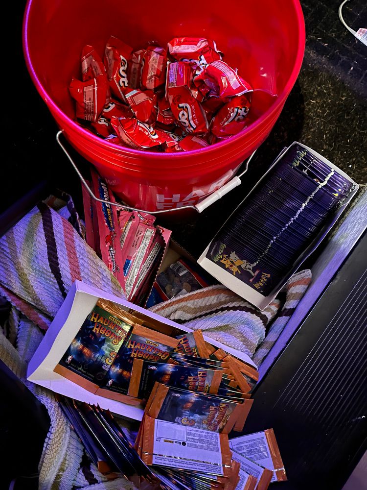 A wide selection of Halloween treats: Fruit by the Foot, Pokémon cards, ans basketball cards, with Nerds Ropes hidden under a towel. 