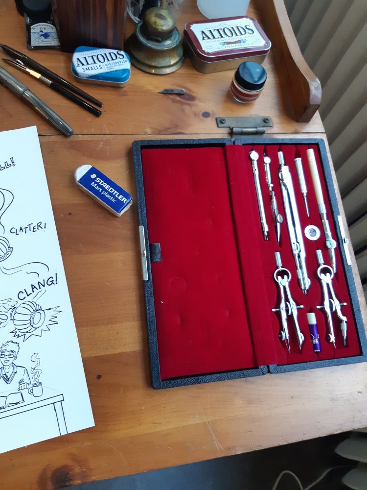 An open case of shining silver drafting instruments swaddled in red velvet.