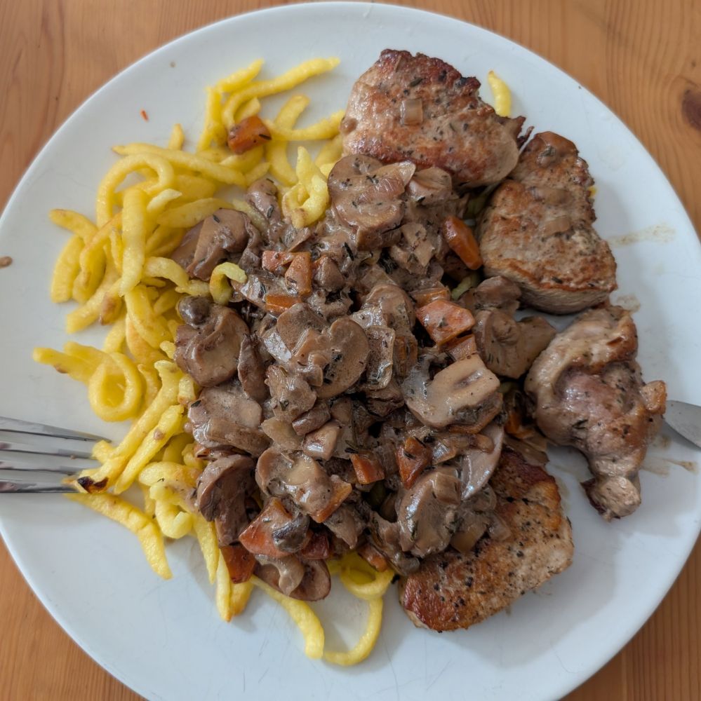 Teller mit Spätzle, dazu Schweinemedaillons und eine Pilz-Rahm-Soße mit Möhren.