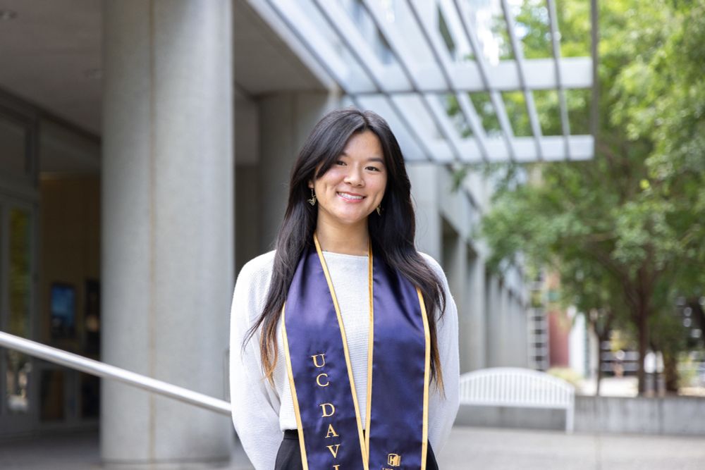Hong stands outdoors near a building wearing UC Davis stole