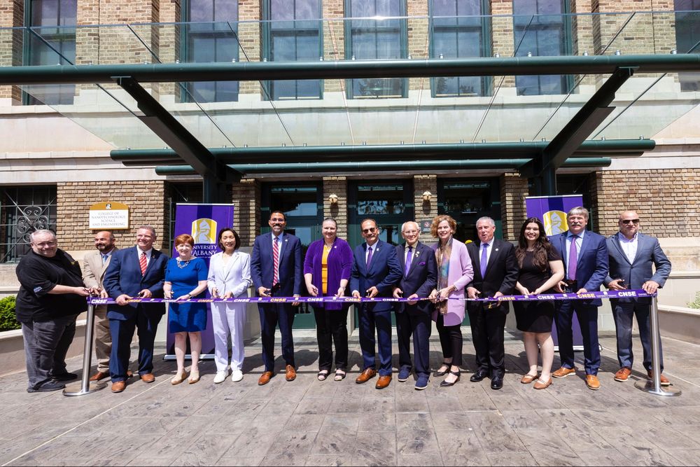 Several people holding a ribbon in front of a building.