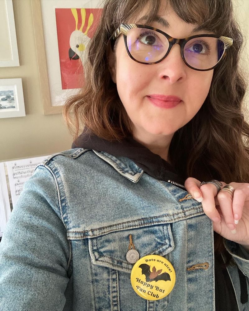 A photo of the artist modeling a happy bat fan club pin