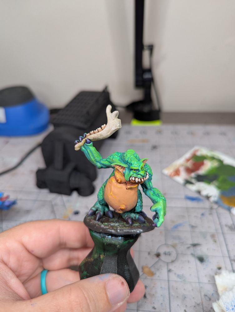A Green troll miniature wielding a moose jaw as a club. The model was painted with acrylic markers rather than a standard brush.